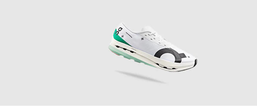 White sneaker with black and green accents on a light gray background