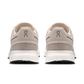 Pair of beige running shoes with white soles on a white background