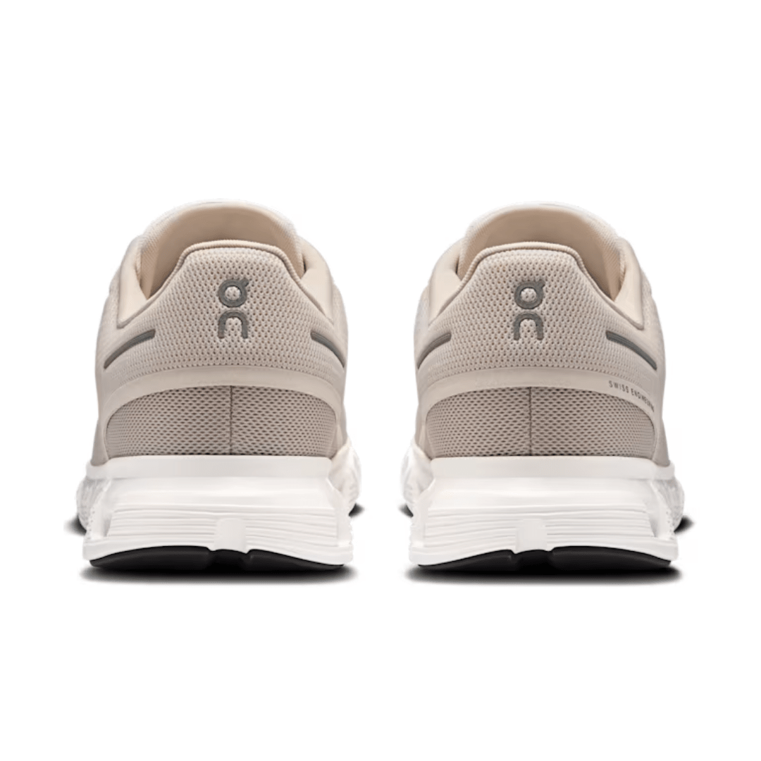 Pair of beige running shoes with white soles on a white background
