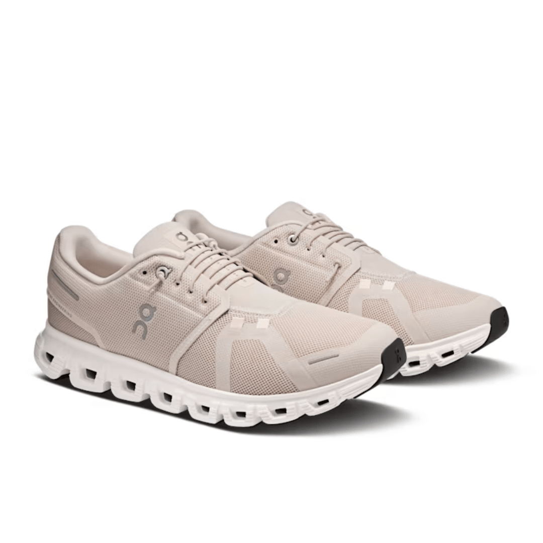 Pair of beige running shoes with white soles on a white background