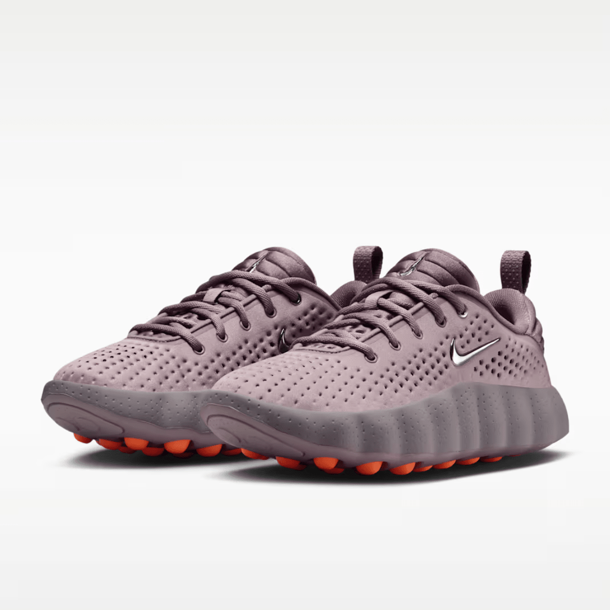 Pair of purple running shoes with orange soles on a white background